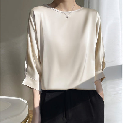 Elegante Damenbluse aus Seide in Cremeweiß, dreiviertel Ärmel, kombiniert mit schwarzer Hose. Stilvolle Mode für Büro und Freizeit.