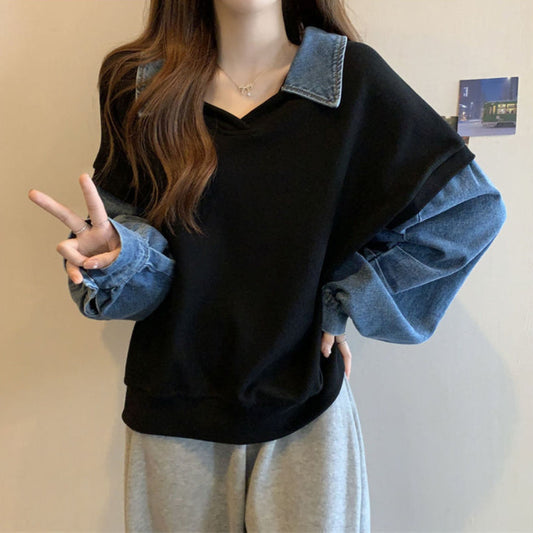 Frau trägt schwarzen Pullover mit blauen Jeansärmeln, zeigt Peace-Zeichen. Modetrend, lässiger Stil, Streetwear, Damenmode.