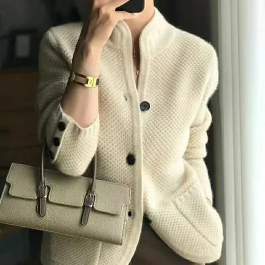 Dame in cremefarbener Strickjacke mit Knöpfen, hält beige Handtasche. Elegante Mode, Herbst-Outfit, stilvolle Damenbekleidung.