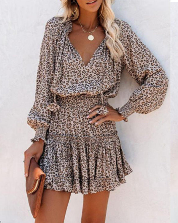 Frau in modischem Leopardenmuster-Kleid mit langen Ärmeln, hält eine braune Clutch. Trendige Damenmode, elegantes Outfit, Sommerlook.