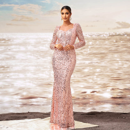 Elegante Frau in funkelndem, rosa Paillettenkleid am Strand bei Sonnenuntergang, glamouröse Abendmode, stilvolle Strandkulisse, modisches Abendkleid.