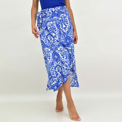 Frau trägt blauen Wickelrock mit weißem Paisley-Muster, knöchellang, barfuß. Sommermode, Damenrock, elegantes Design, Freizeitkleidung.