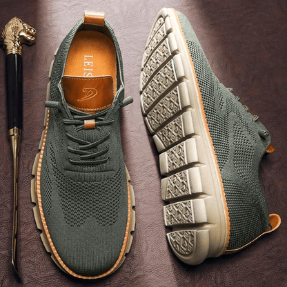 Grüne Herren-Sneaker mit gestricktem Obermaterial und dicker, rutschfester Sohle auf braunem Hintergrund. Bequeme, modische Freizeitschuhe.