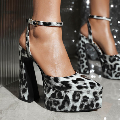 Leopardenmuster High Heels mit Plateau, Knöchelriemen und Blockabsatz auf glänzendem Boden. Modische Damenschuhe, trendiges Design.