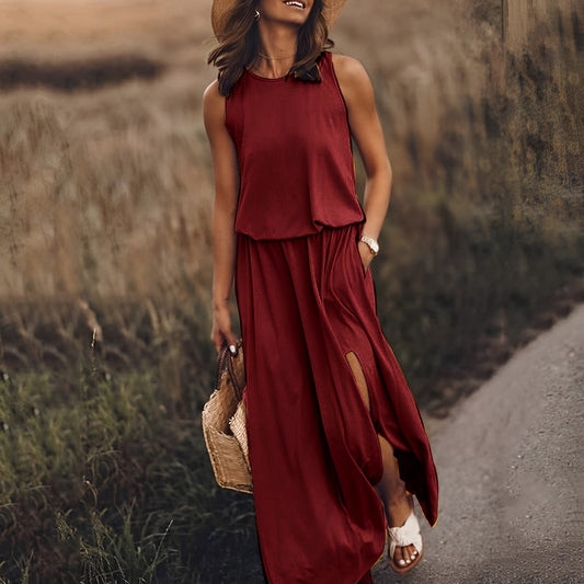Frau in rotem Maxikleid mit Schlitz, Strohhut und Sandalen auf einem ländlichen Weg. Sommermode, Boho-Stil, Freizeitkleidung.