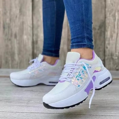 Damen-Sneaker mit weißem und lila Design, schimmernden Details, getragen mit blauen Jeans. Modische Sportschuhe, ideal für Freizeit und Sport.
