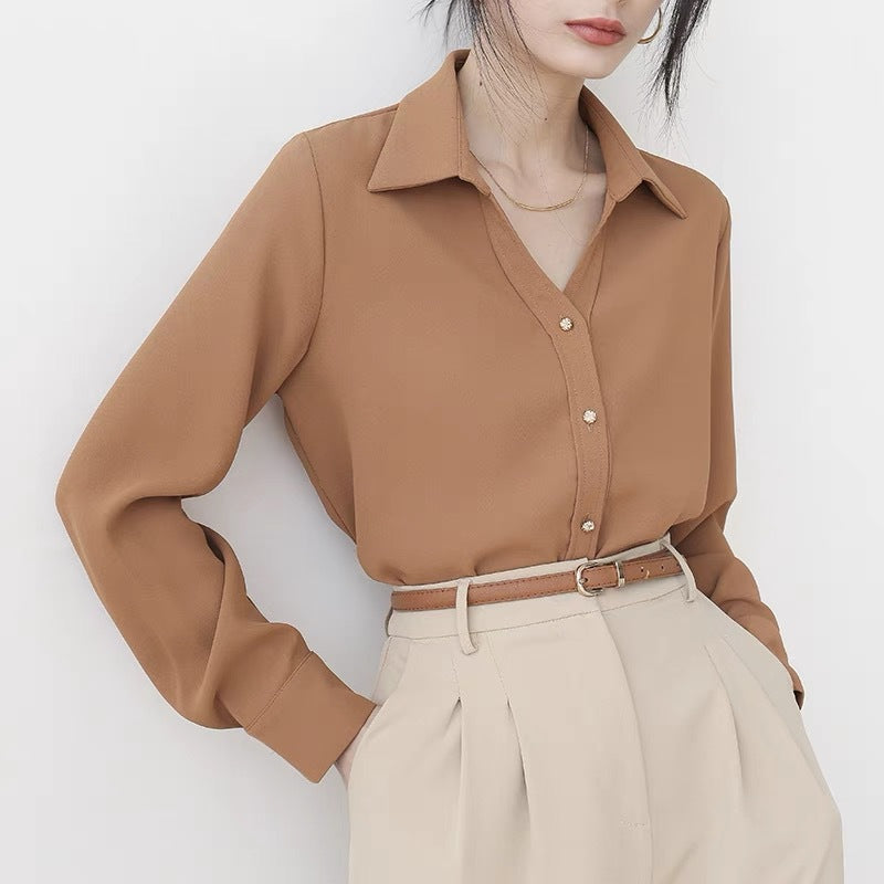 Frau in eleganter, brauner Bluse mit Knopfleiste und beigen, hoch taillierten Hosen. Modetrend, Damenmode, stilvolle Büro-Outfits.