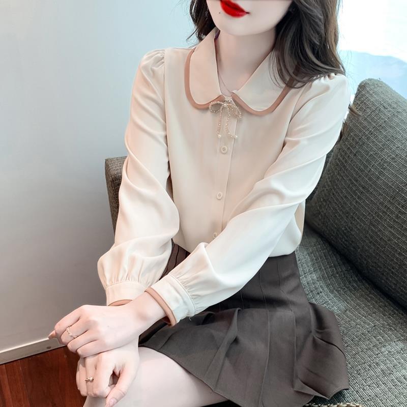 Frau in eleganter weißer Bluse mit Kragen und braunem Rock sitzt auf Sofa. Mode, Damenbekleidung, stilvolle Büro-Outfits.