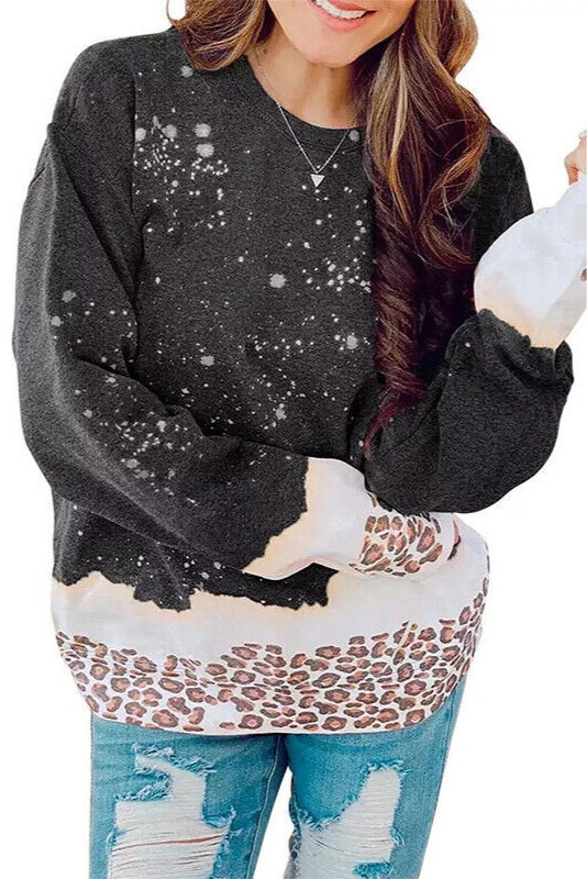 Frau trägt schwarzen Pullover mit Schneeflocken- und Leopardenmuster, kombiniert mit zerrissenen Jeans. Modetrend, Winteroutfit, Damenmode.