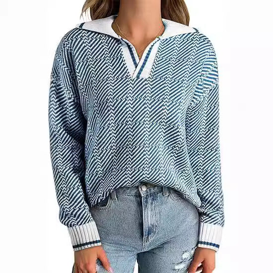 Frau trägt blauen Strickpullover mit Zickzackmuster und weißen Details, kombiniert mit hellblauen Jeans. Modetrend, Damenmode, Herbstoutfit.