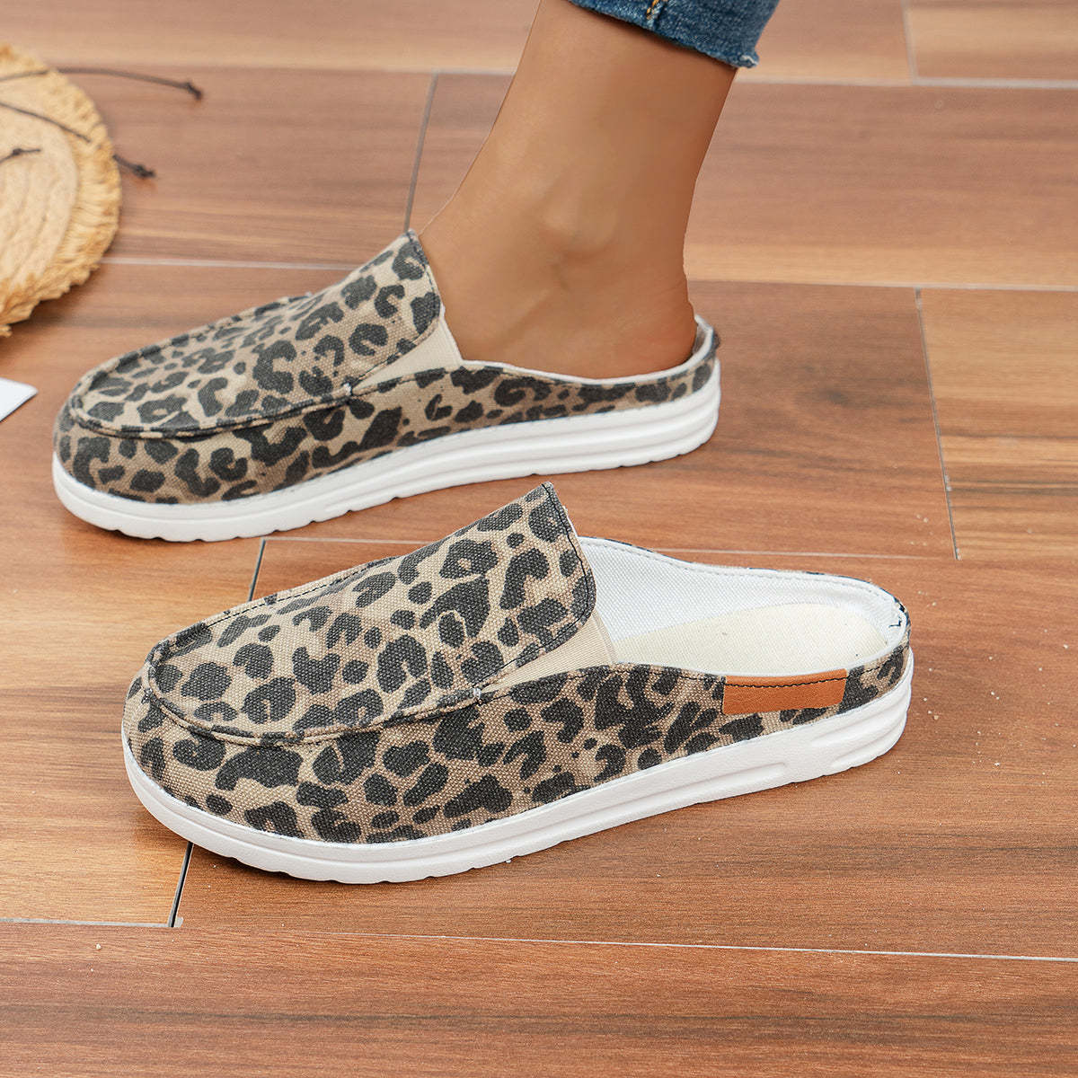 Leopardenmuster-Slipper auf Holzboden, Damenmode, bequeme Freizeitschuhe, trendige Tierprint-Schuhe, lässiger Stil, modische Fußbekleidung.