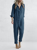 Frau in lockerem, dunkelblauem Jumpsuit vor grauem Hintergrund. Modetrend, lässiger Einteiler, Damenbekleidung, Freizeitlook.