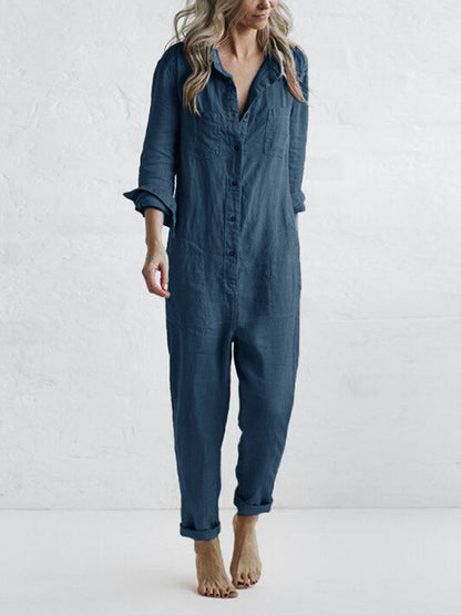 Frau in dunkelblauem Leinen-Jumpsuit, lässig und bequem, barfuß, vor weißem Hintergrund. Modetrend, Damenbekleidung, Freizeitlook.