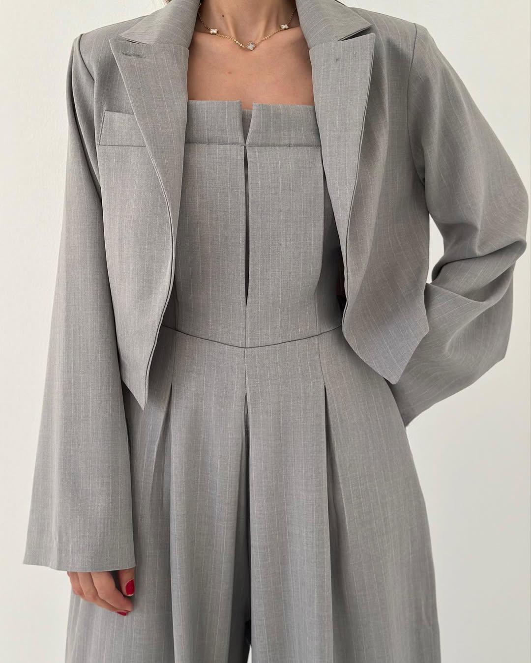 Grauer Damenanzug mit Blazer und ärmellosem Oberteil, elegantes Business-Outfit, moderne Damenmode, stilvoller Look für Büro und formelle Anlässe.