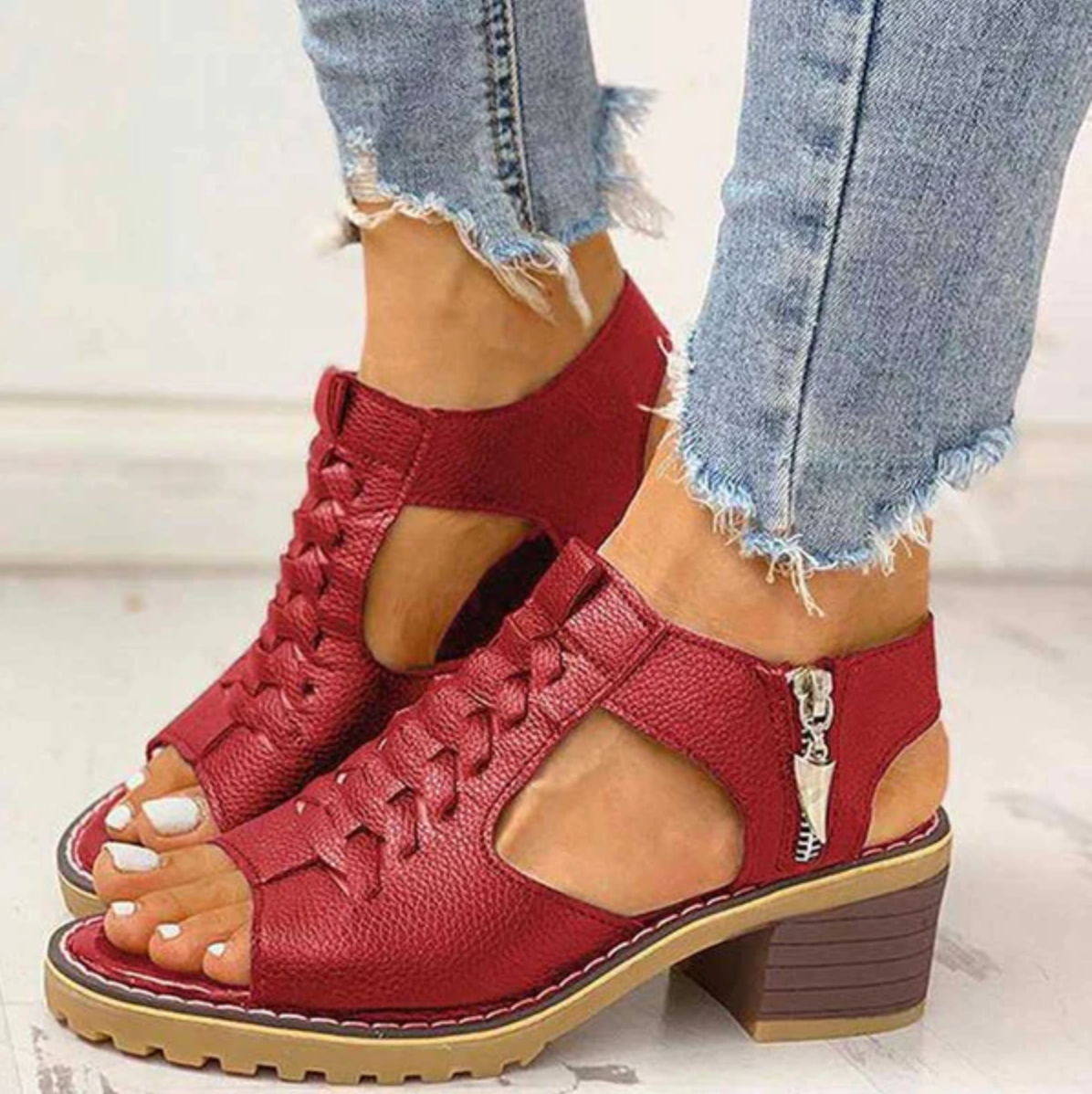 Rote Damen-Sandalen mit Blockabsatz und geflochtenem Design, kombiniert mit ausgefransten Jeans. Modische Sommerschuhe für Frauen.