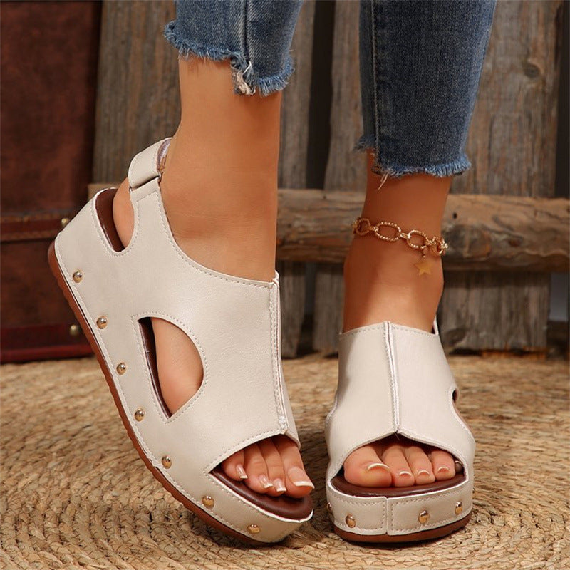 Beige Sandalen mit Cut-Out-Design und Nieten, getragen von einer Person mit Jeans. Modische Sommerschuhe, ideal für lässige Outfits.