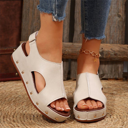 Beige Sandalen mit Cut-Out-Design und Nieten, getragen von einer Person mit Jeans. Modische Sommerschuhe, ideal für lässige Outfits.