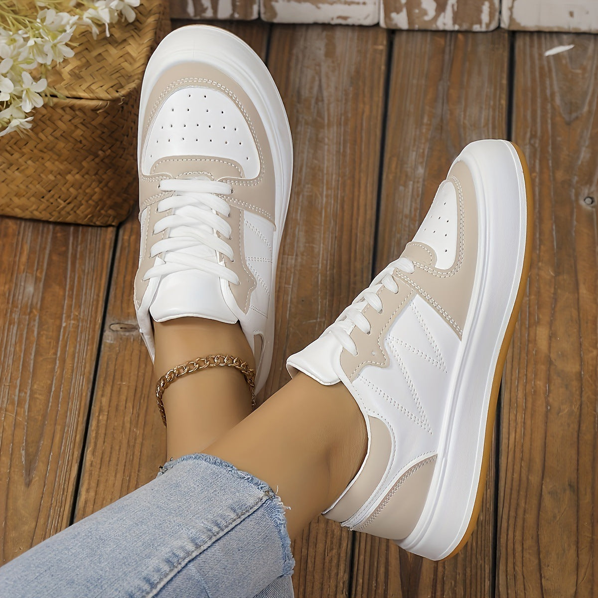 Weiße und beige Sneaker auf Holzboden, getragen von Person in blauen Jeans. Modische Damen-Sneaker, lässiger Stil, ideal für Freizeitoutfits.