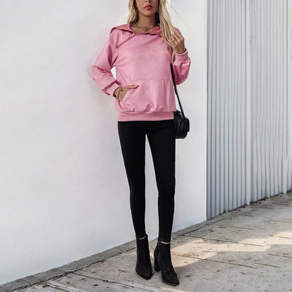 Frau in rosa Hoodie und schwarzer Hose, steht vor weißer Wand. Modetrend, lässiger Stil, Herbstmode, Streetwear, Damenbekleidung.