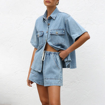 Frau in lässigem Jeans-Set mit Hemd und Shorts vor weißer Wand. Modetrend, Sommeroutfit, Denim-Look, Freizeitkleidung.
