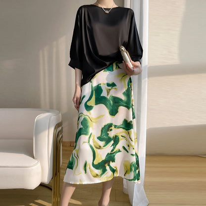 Elegantes Damenkleid mit schwarzem Oberteil und grün-gelbem abstraktem Muster auf weißem Rock, ideal für stilvolle Anlässe und moderne Mode.