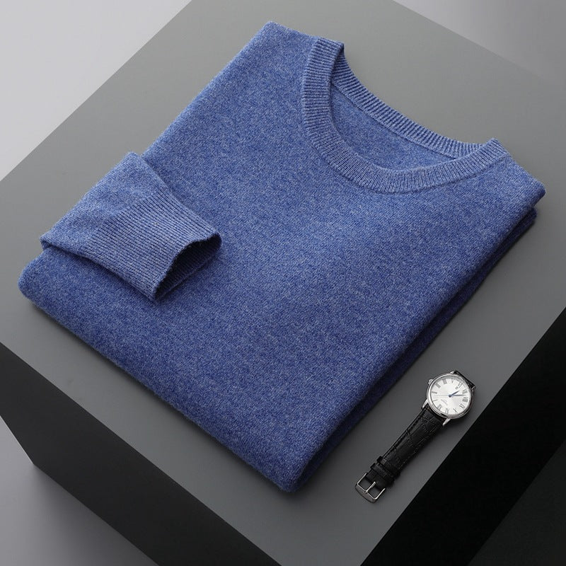 Blauer Kaschmirpullover auf grauem Tisch, daneben eine elegante Armbanduhr. Hochwertige Mode, Luxuskleidung, stilvolle Accessoires.