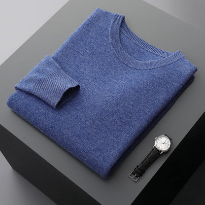 Blauer Kaschmirpullover auf grauem Tisch, daneben eine elegante Armbanduhr. Hochwertige Mode, Luxuskleidung, stilvolle Accessoires.