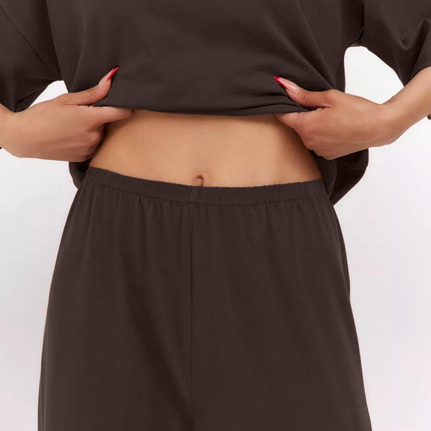 Frau zeigt Bauch in braunem Outfit, hebt Oberteil an. Mode, Bauch, Kleidung, Freizeitlook, Damenmode, braunes Outfit, lässiger Stil.