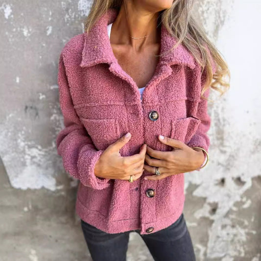 Frau in rosa Teddyjacke vor Betonwand, modische Herbstbekleidung, kuscheliger Stoff, lässiger Stil, Damenmode, Outdoor-Jacke.