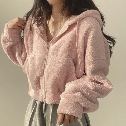 Frau in rosa Teddyfleece-Jacke mit Kapuze und Reißverschluss, lässiger Stil, gemütlich und modisch, ideal für Herbst- und Wintermode.