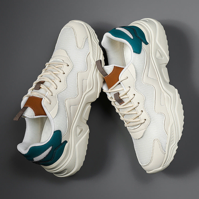 Weiße Chunky Sneaker mit dicker Sohle, braunen und grünen Akzenten auf grauem Hintergrund. Modische Turnschuhe, trendige Sportschuhe.