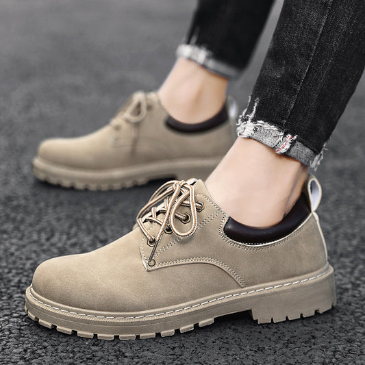 Beige Herrenschuhe aus Wildleder mit Schnürsenkeln, getragen zu schwarzen Jeans auf Asphalt. Modische, robuste Freizeitschuhe für Männer.