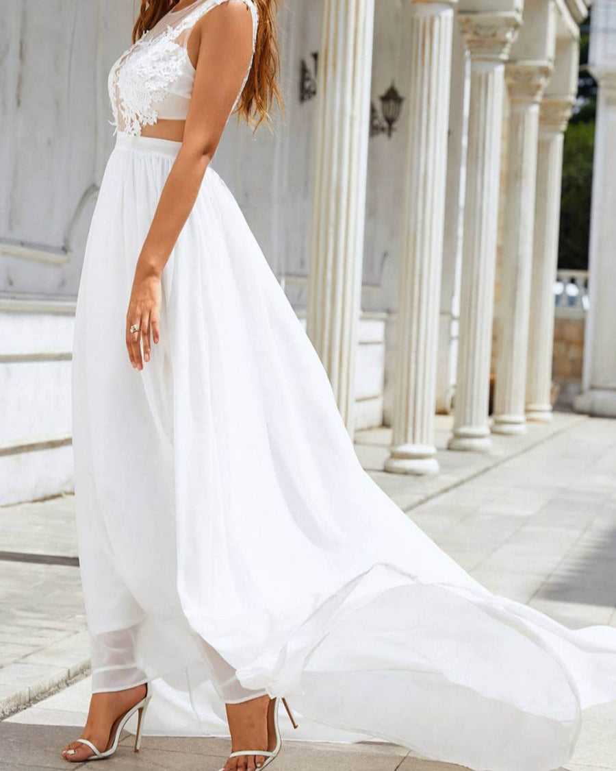 Braut in elegantem, weißem Hochzeitskleid mit Spitzenoberteil und fließendem Rock, posiert vor antiken Säulen. Perfekt für Sommerhochzeiten.