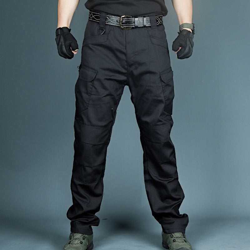 Schwarze taktische Hose mit mehreren Taschen, getragen von Person in schwarzem Outfit und Handschuhen, ideal für Outdoor-Aktivitäten und Sicherheit.