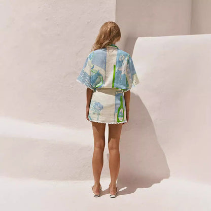 Frau in sommerlichem, gemustertem Zweiteiler vor weißer Wand, Rückenansicht. Modetrend, Sommeroutfit, Damenmode, stilvoll, lässig.