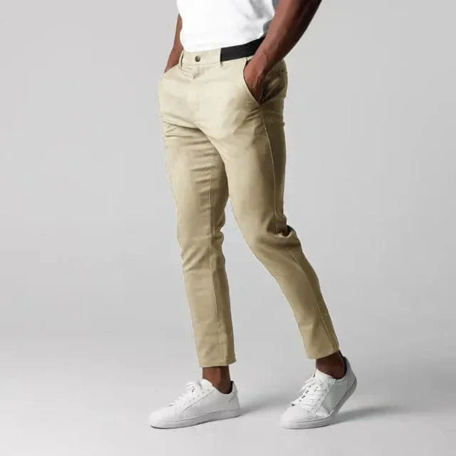 Herrenmode: Beige Chinohose, weißes T-Shirt, weiße Sneaker. Stilvolle Freizeitkleidung für Männer. Eleganter Look, moderne Herrenbekleidung.