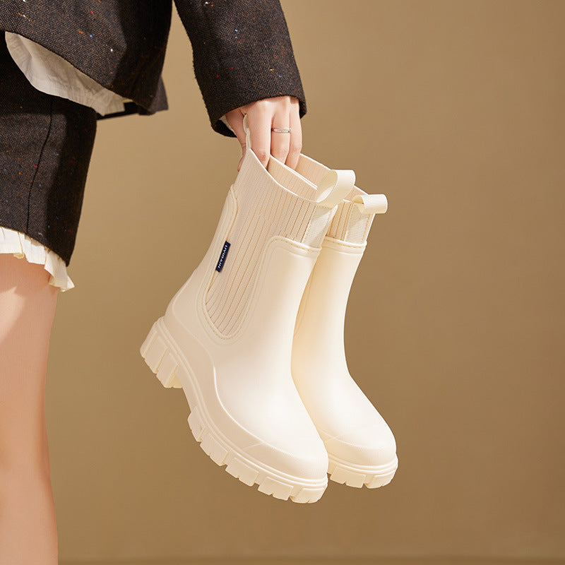 Beige Gummistiefel mit dicker Sohle, von Hand gehalten. Modische, wasserdichte Stiefel für Damen. Ideal für Regenwetter und Outdoor-Aktivitäten.