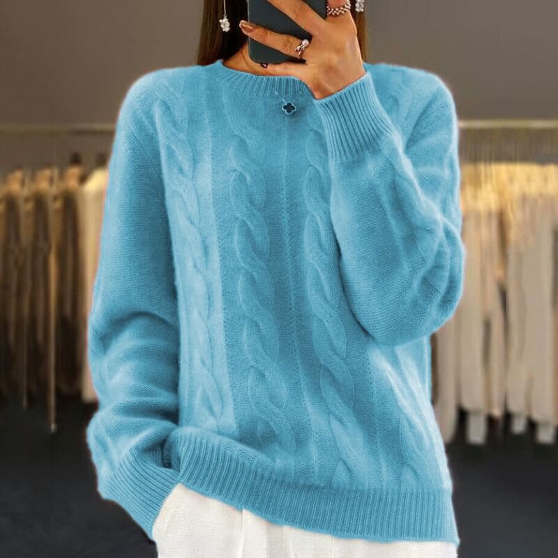 Frau in blauem Zopfmuster-Pullover, hält Smartphone, steht vor Kleiderständern. Modetrend, Wintermode, Strickpullover, Damenbekleidung.