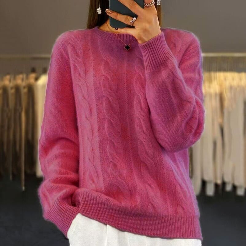 Frau trägt pinken Strickpullover mit Zopfmuster, modisch und elegant, ideal für Herbstmode. Perfekt kombiniert mit weißer Hose.