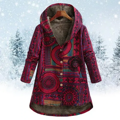 Bunte Damen-Winterjacke mit Kapuze, ethnisches Muster, Knopfleiste, warmes Futter, vor schneebedecktem Waldhintergrund. Perfekt für kalte Tage.