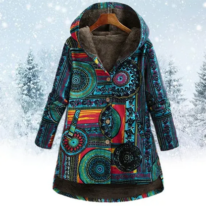 Bunte Damen-Winterjacke mit Kapuze, ethnisches Muster, warm gefüttert, vor schneebedecktem Wald. Ideal für kalte Wintertage.