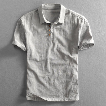 Graues Leinen-Poloshirt mit kurzen Ärmeln und Knopfleiste, auf grauem Hintergrund. Ideal für Herrenmode, Sommerkleidung, Freizeitlook.