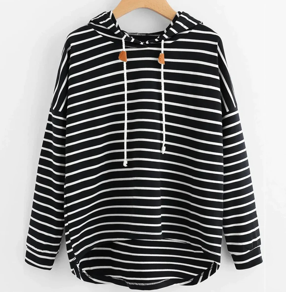 Schwarz-weiß gestreifter Kapuzenpullover mit Kordelzug, lässiger Stil, hängend auf Holzkleiderbügel. Modischer Hoodie für Damen.