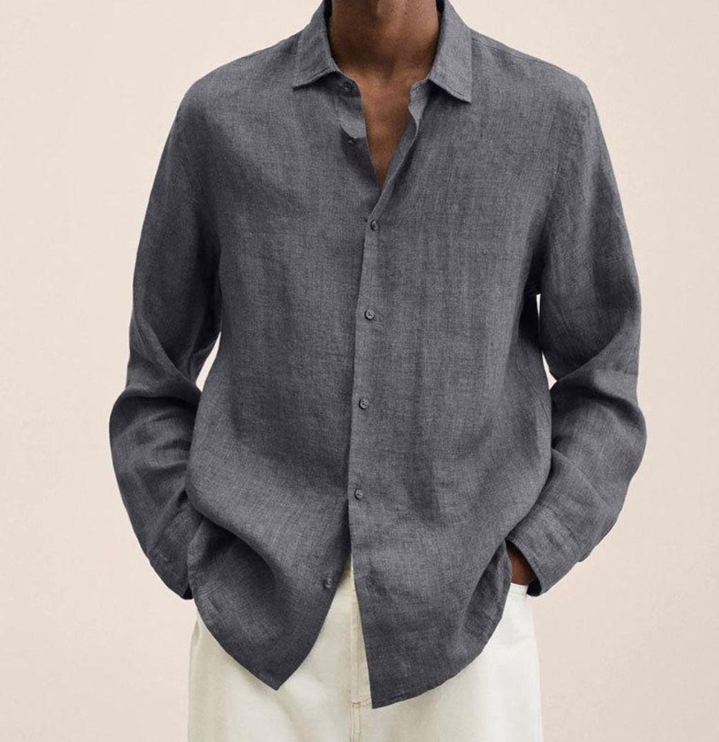 Graues Leinenhemd für Herren, lässig offen getragen, kombiniert mit weißen Hosen. Stilvolle Herrenmode, ideal für Sommer und Freizeit.