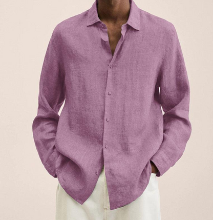 Mann trägt lila Leinenhemd, lässig offen, mit weißen Hosen. Stilvolle Herrenmode, ideal für Sommer und Freizeit. Elegantes, atmungsaktives Design.