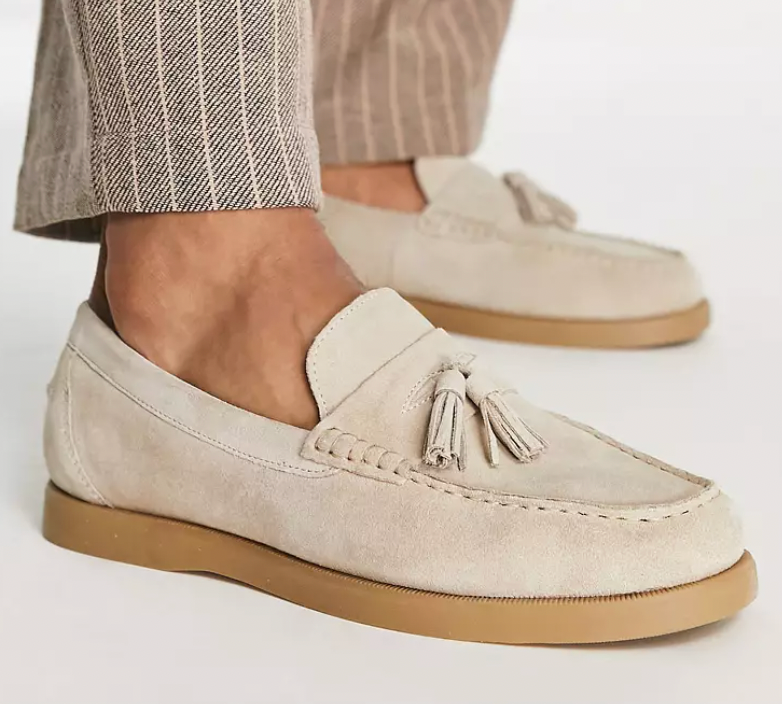 Beige Wildleder-Loafer mit Quasten, getragen von einer Person in gestreiften Hosen. Modische Herrenschuhe, ideal für elegante Freizeitoutfits.
