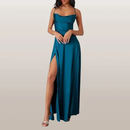 Frau in elegantem, blauem Abendkleid mit hohem Beinschlitz und Spaghettiträgern, trägt weiße High Heels. Perfekt für formelle Anlässe.