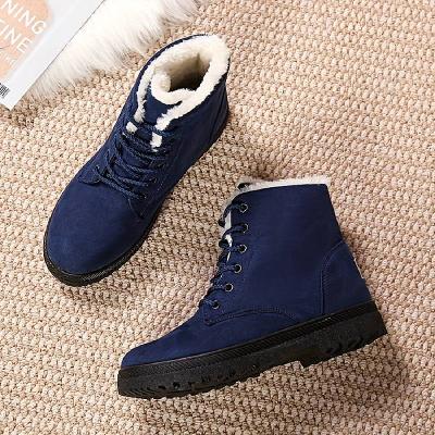 Blaue Winterstiefel mit weißem Kunstfellfutter auf beigem Teppich. Modische, warme Damenstiefel, ideal für kalte Jahreszeiten.