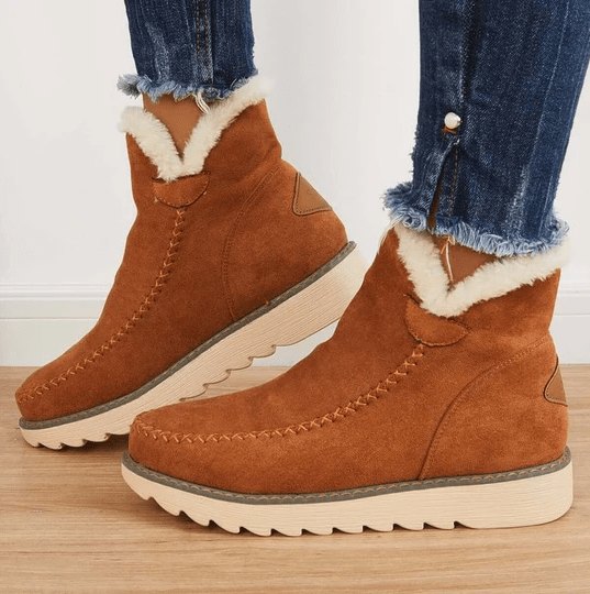 Braune Wildleder-Winterstiefel mit weißem Kunstfellfutter, getragen mit blauen Jeans. Bequeme, warme Damenstiefel für kalte Tage.