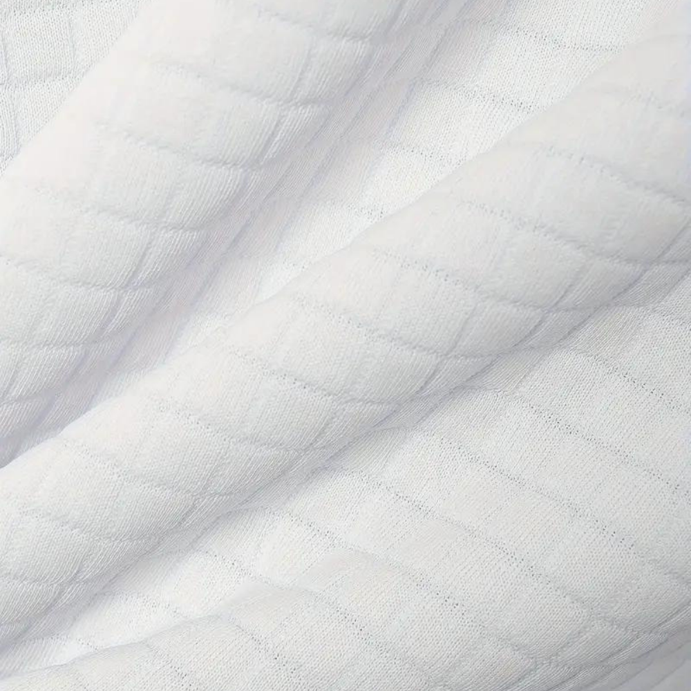 Weiße, gesteppte Stoffstruktur, Nahaufnahme. Weicher, texturierter Baumwollstoff, ideal für Bettwäsche oder Kleidung. Hochwertiges Material.